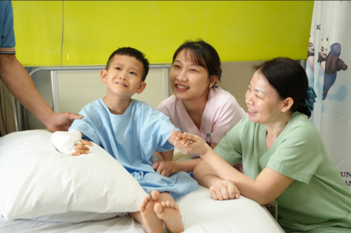 Bé Duy Quang sau khi được phẫu thuật tay phải, đặt bộ khung để kéo xương.